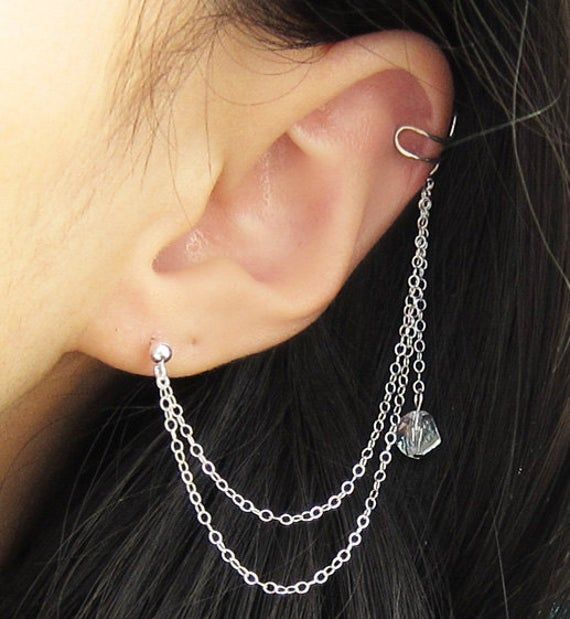 "This sterling silver earring features a Swarovski helix crystal with a long sterling silver double chain connecting an earring stud to an ear cuff forming this Sterling Silver Crystal Dangle Long Double Chain Cuff Earring. This ear cuff requires no piercing so anyone with just one ear lobe piercing can wear this earring. The ear cuff is similar to a clip-on earring where it cuffs onto the ear but this goes onto the upper (helix or rim) cartilage or middle cartilage. Then squeeze the ear cuff to Elegant Silver Cartilage Earrings With Chain, Sterling Silver Dangle Ear Cuff For Party, Silver Sterling Silver Ear Climbers For Party, Silver Dangle Chain Cartilage Earrings, Elegant Sterling Silver Ear Cuff With Adjustable Chain, Silver Sterling Ear Cuff With Adjustable Chain, Earring Cuff Chain, Ear Lobe Piercings, Double Earrings