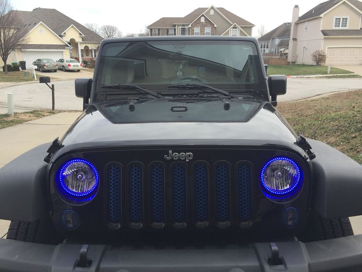 a black jeep with blue leds parked in front of a house