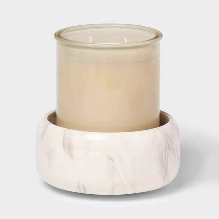 a white candle holder with a marbled base and glass lid, on a grey background