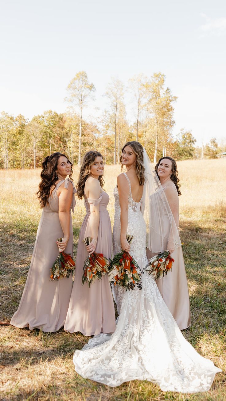 four bridesmaids standing in a field with their bouquets