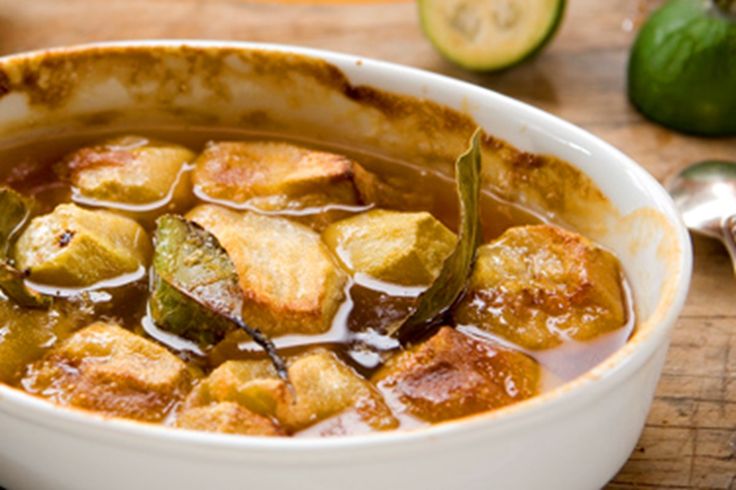 a white bowl filled with soup next to sliced cucumbers