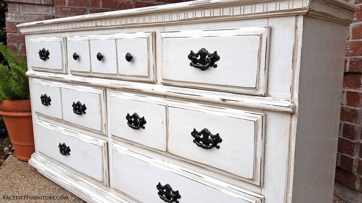 an old white dresser with black knobs on it