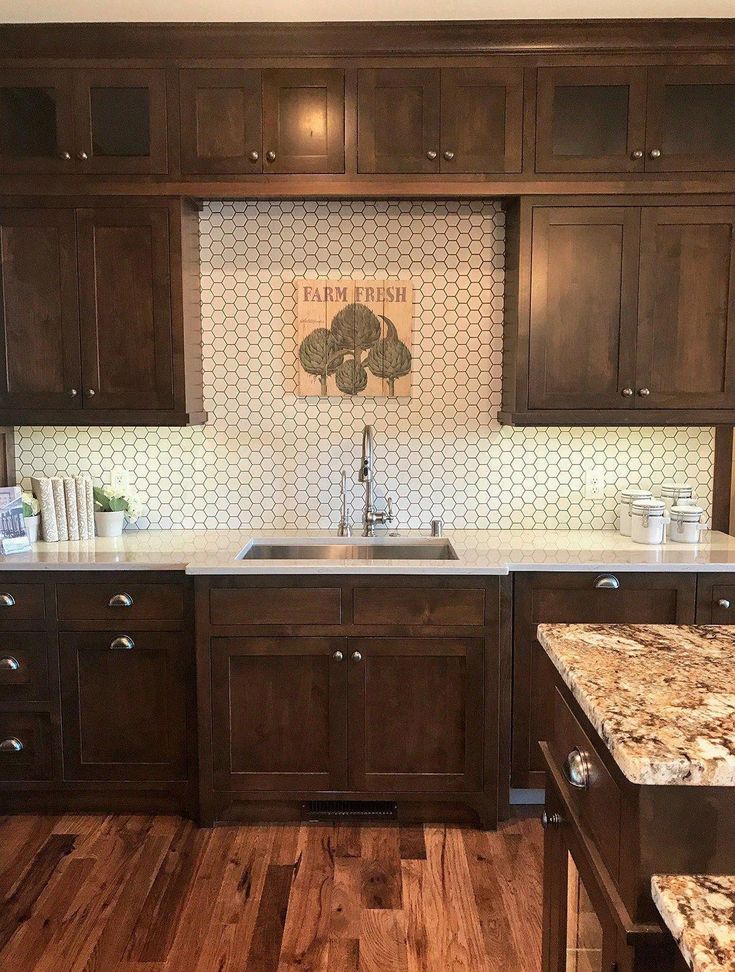 a kitchen with wooden cabinets and marble counter tops in the center, along with wood flooring