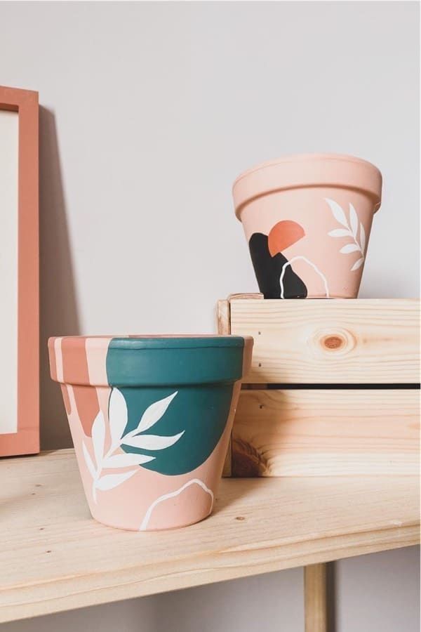 two flower pots sitting on top of a wooden shelf