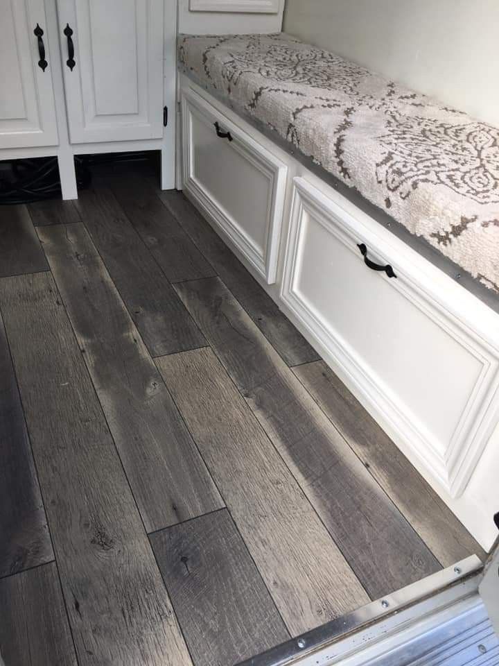 a kitchen with white cabinets and wood flooring on the side of the counter top