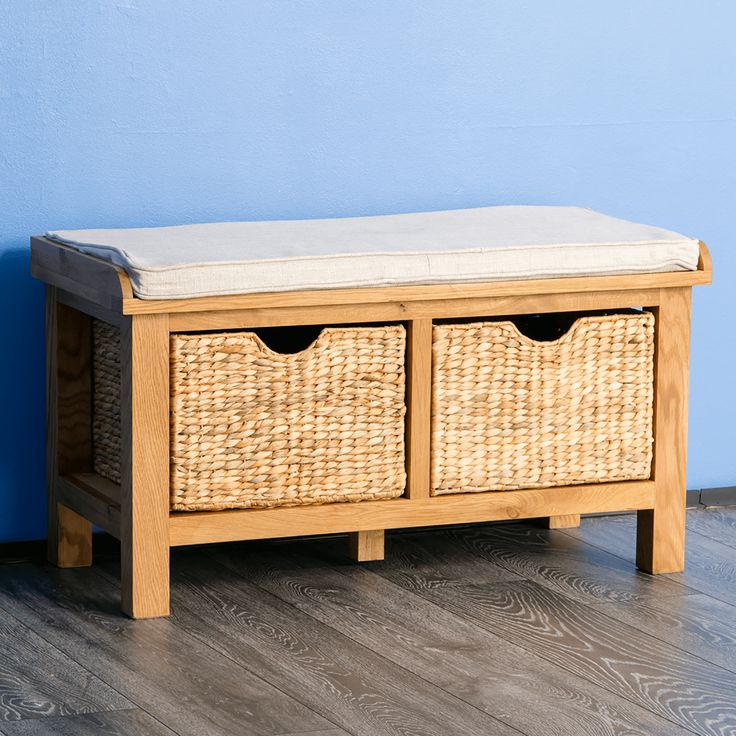 a wooden bench with two wicker baskets on it's sides and a blue wall in the background