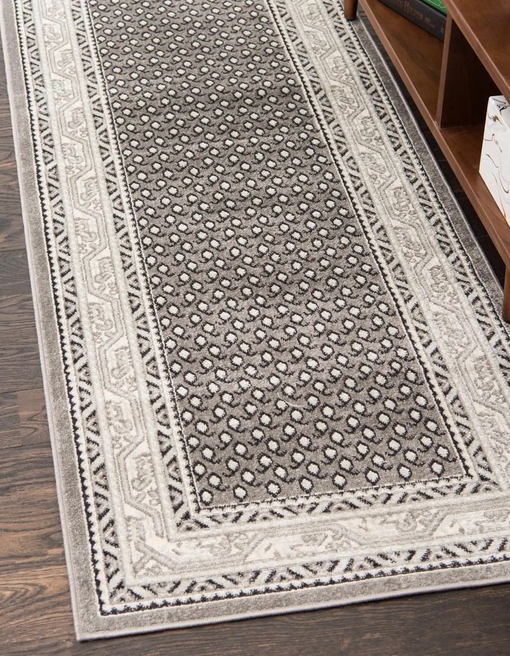 a large rug is on the floor in front of a book shelf and desk with drawers