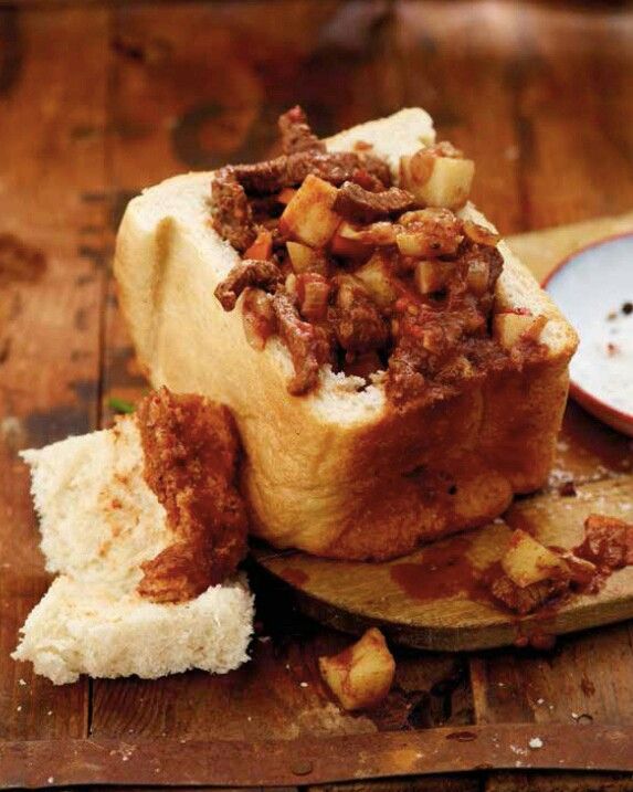 a sandwich with meat and bread on a cutting board