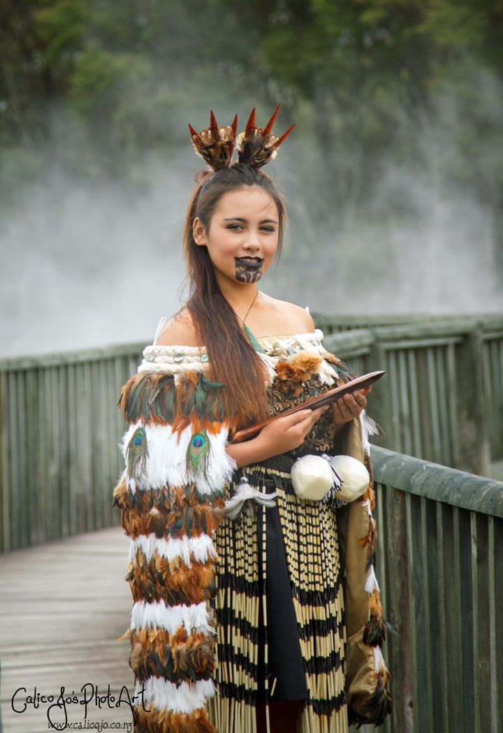 a woman dressed in native american clothing standing on a bridge