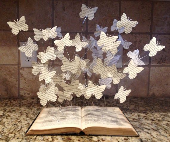 an open book sitting on top of a counter next to a bunch of paper butterflies