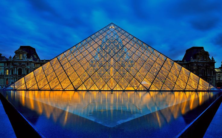 the pyramid is lit up at night in front of some buildings