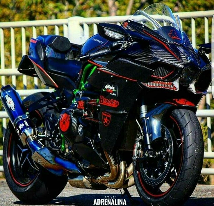 a black motorcycle parked next to a white fence