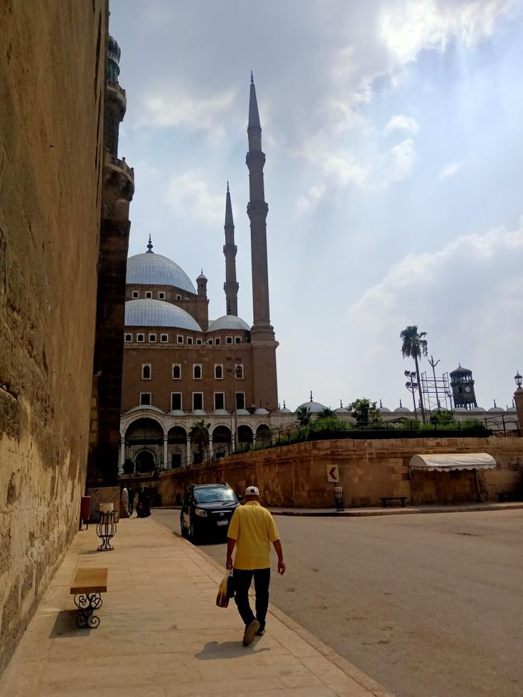 a man walking down the street in front of a building with a large dome on it