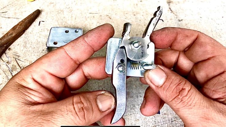 two hands holding a pair of pliers in front of some tools on the ground