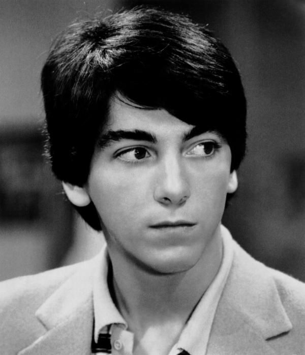 black and white photograph of young man in suit looking at camera with serious look on face