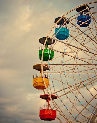 the ferris wheel is brightly colored and has lights on it's sides as well