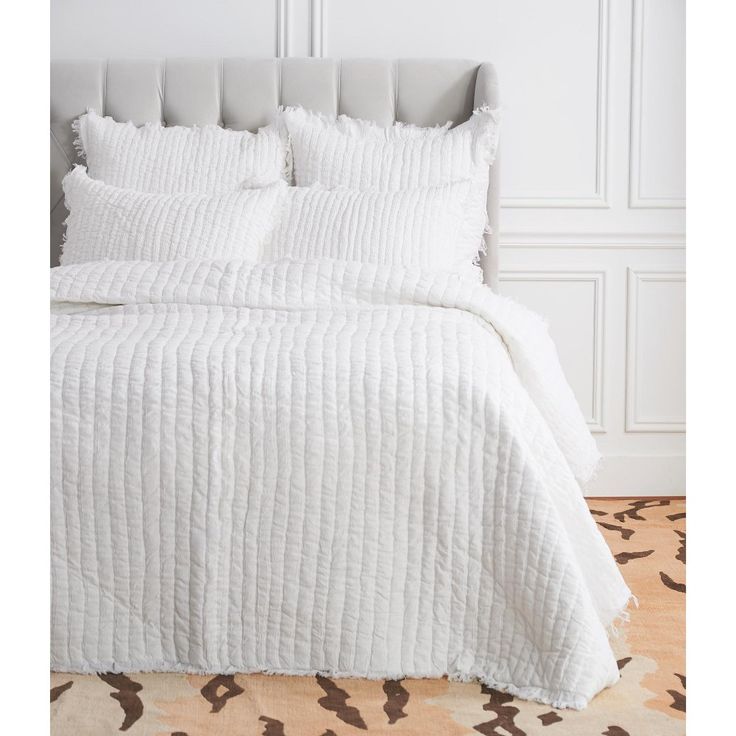 the bed is made with white linens and pillows on top of it, along with an animal print area rug