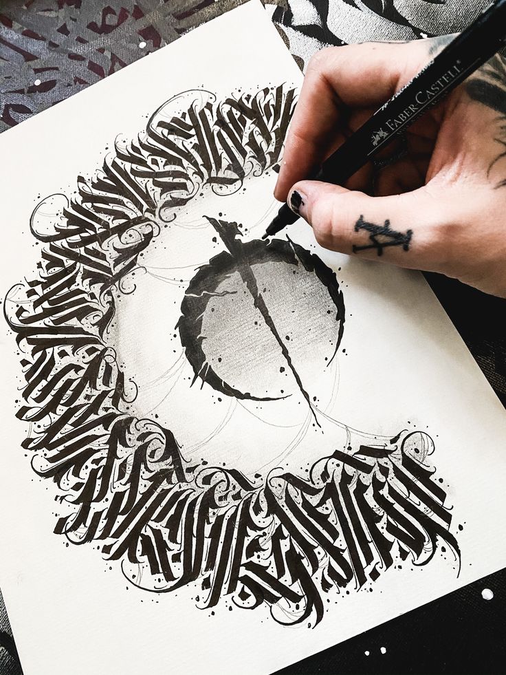 a person is holding a pen and drawing something in black ink on a white paper