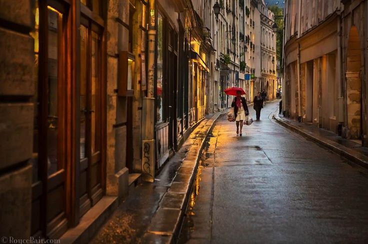 two people walking down an alleyway with umbrellas on a rainy day in the city