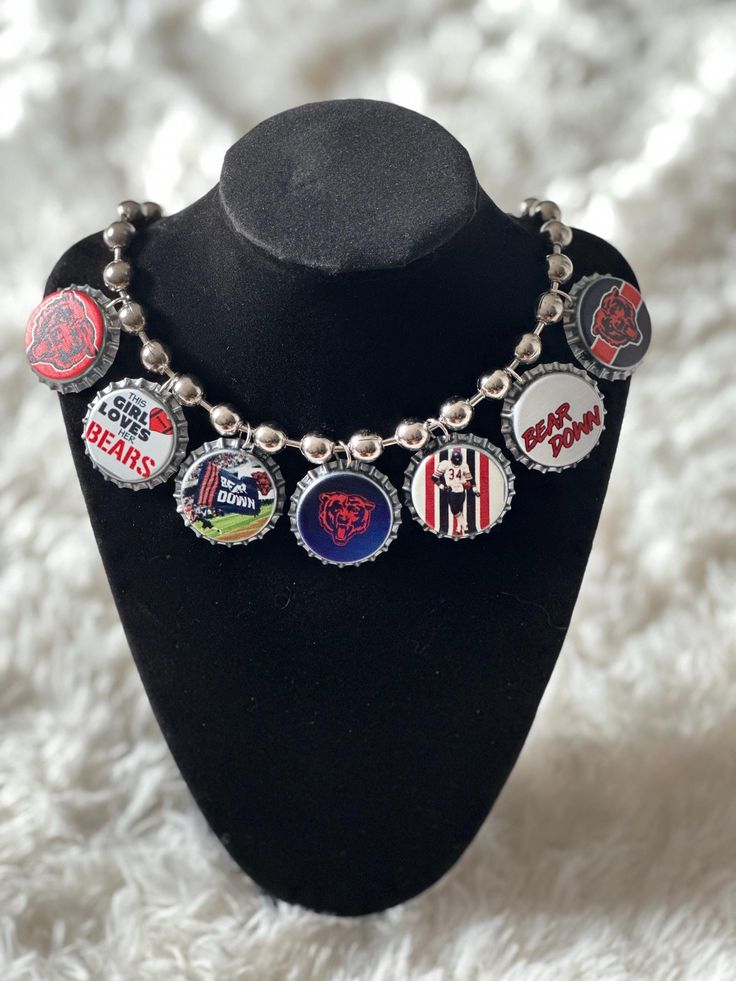 a black mannequin wearing a necklace with various badges and letters on the front