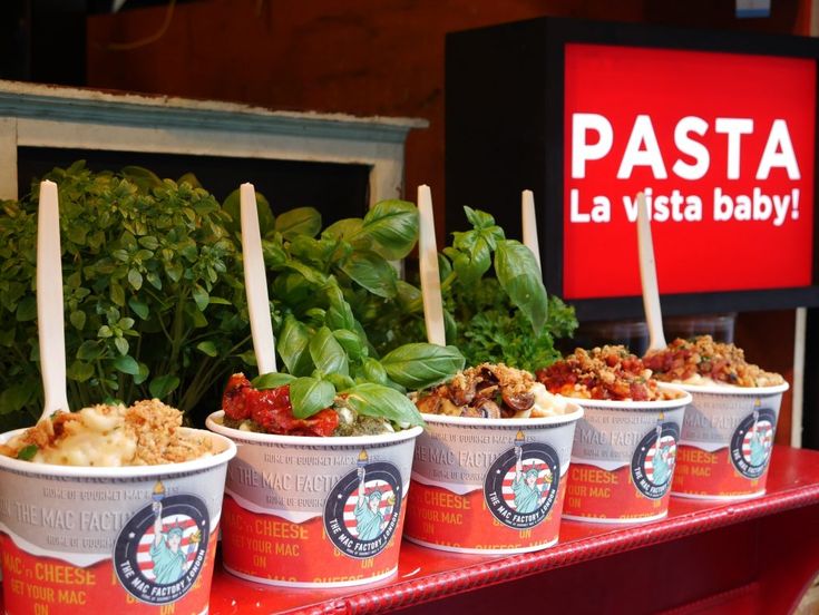 three cups filled with food sitting on top of a red table next to a sign that says pasta la vista baby