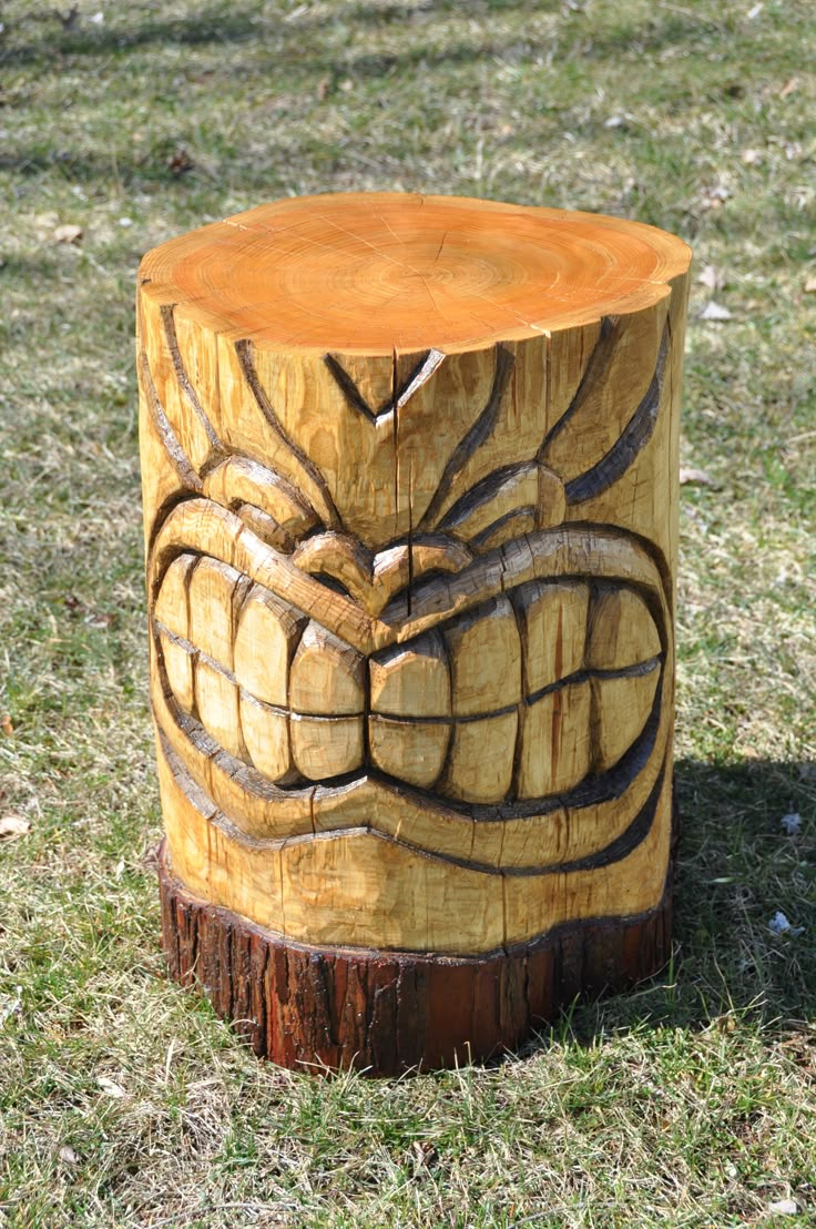 a carved wooden stool sitting on top of a lush green field