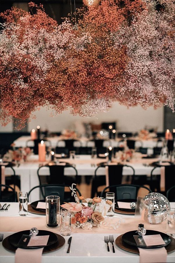 the tables are set with black and white linens, silverware, and pink flowers