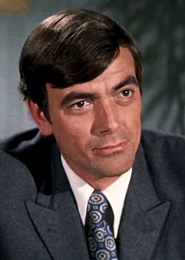 a close up of a person wearing a suit and tie with a serious look on his face