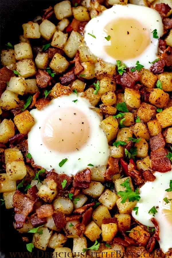 two fried eggs on top of potatoes in a skillet