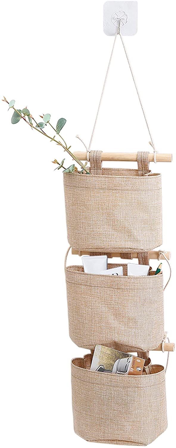 three hanging baskets filled with items on top of a white wall and one holding a plant