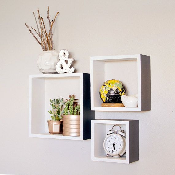 two white shelves with plants and an alarm clock