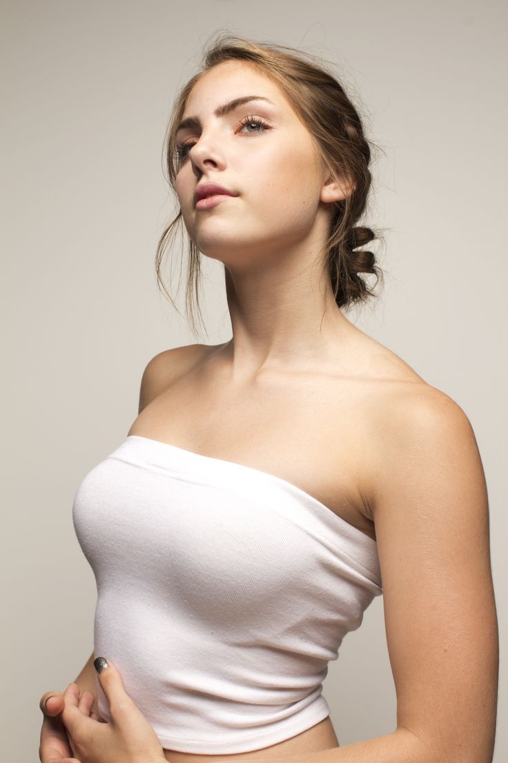 a woman in a white top is holding her hand on her hip and looking up