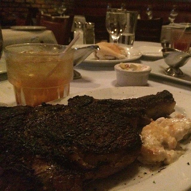 a plate with steak, potatoes and drinks on the side at a table in a restaurant