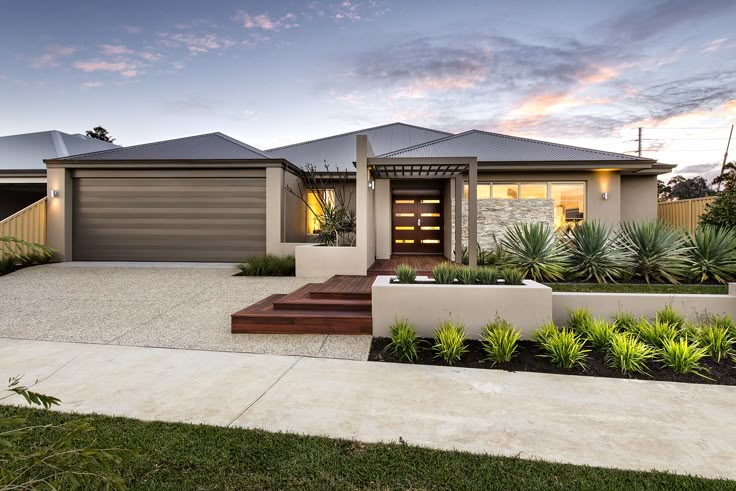 a modern house with landscaping in the foreground and an entrance to the front yard