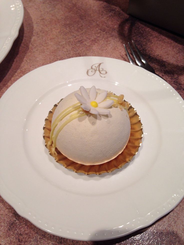 a white plate topped with a pastry covered in icing and flowers on top of it