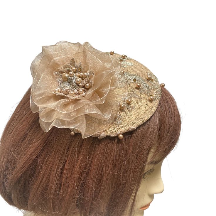 "An antique gold fascinator is covered with intricate beaded gold lace. A champagne colored handmade beaded flower sits on one end and this small elegant hat or gold fascinator is perfect for a formal event. This versatile piece can be worn in many ways. If you choose to have it mounted on a headband it will be fixed on the headband and will be able to be worn on either side of your head. The golden mini hat attaches to your hair with an alligator clip attached to the underside or a satin wrappe Handmade Gold Hat For Kentucky Derby, Gold Adjustable Headpiece With Structured Crown, Gold Round Crown Headpiece For Weddings, Gold Wedding Headpiece With Round Crown, Elegant Handmade Headpiece With Structured Crown, Gold Crown Costume Headpiece For Weddings, Handmade Gold Headpiece With Pinched Crown, Gold Beaded Wedding Headpieces, Evening Headpiece With Handmade Flowers And Pinched Crown