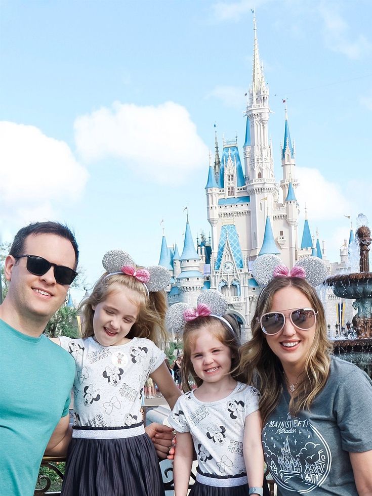 a family poses for a photo in front of the castle at disney world with minnie mouse ears