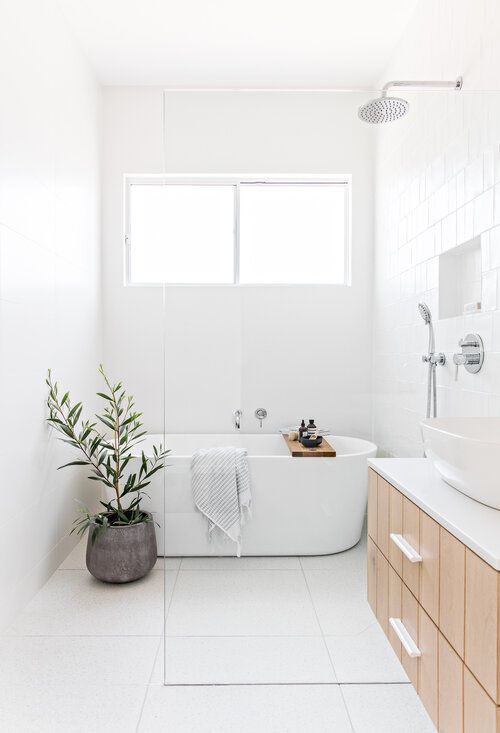 a white bathroom with a tub, sink and mirror in it's center area