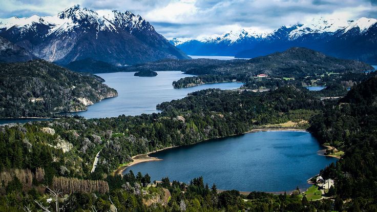 an aerial view of a lake surrounded by mountains and snow capped peaks in the distance