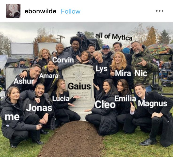 a group of people posing for a photo in front of a grave with names on it