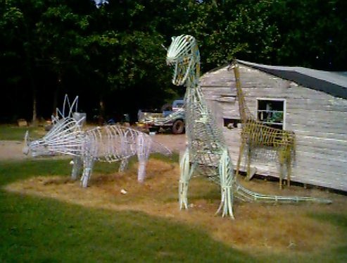 two metal zebras are standing in the grass next to a shed and tree line