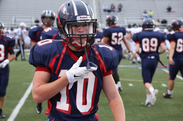 a football player is walking off the field with his hand on his hip and other players behind him