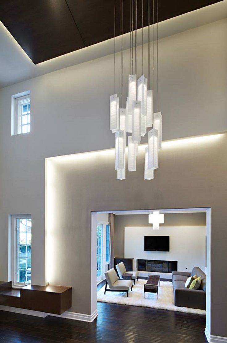 a modern living room with wood flooring and white walls, chandelier hanging from the ceiling