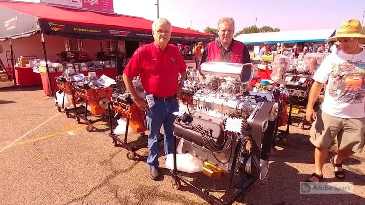 two men are looking at an engine on a cart in the middle of a parking lot