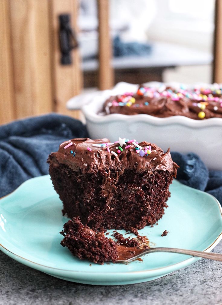 a piece of chocolate cake with sprinkles on a blue plate next to a fork