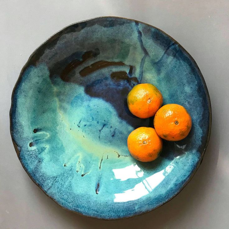 three oranges in a blue bowl on a table