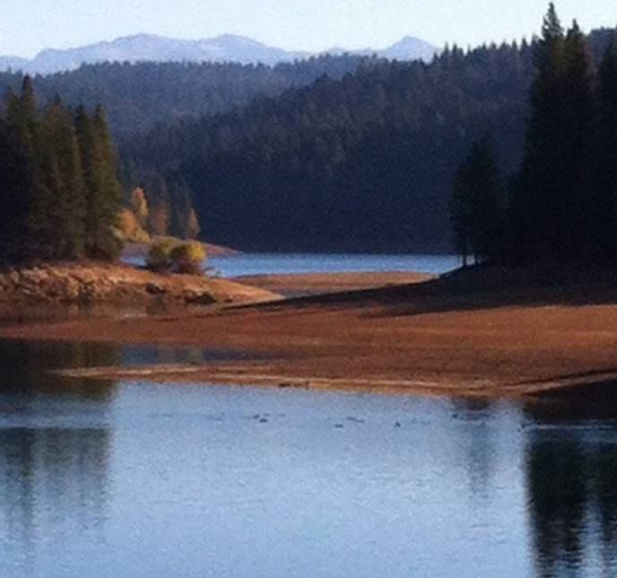 there is a boat on the water in the middle of the lake with mountains in the background