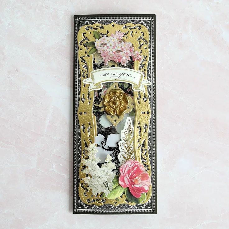 a card with flowers on it and a ribbon hanging from the front, in gold foil