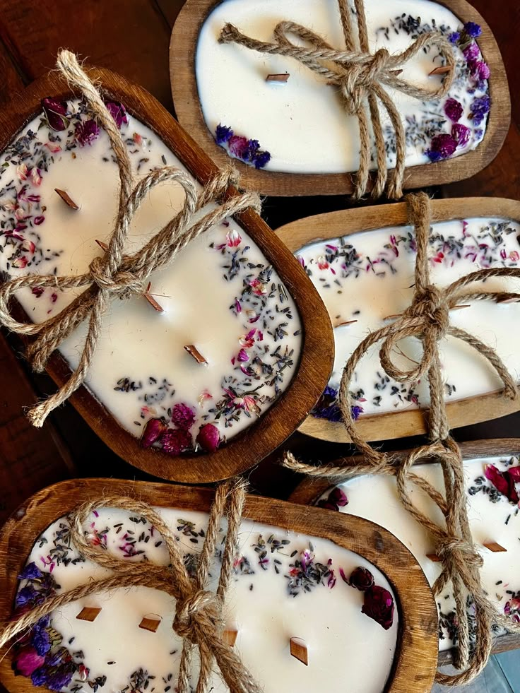 four wooden trays filled with white candles and dried flowers on top of each other