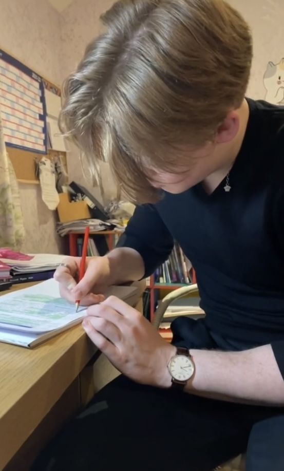 a woman sitting at a desk writing on a piece of paper with a watch on her wrist